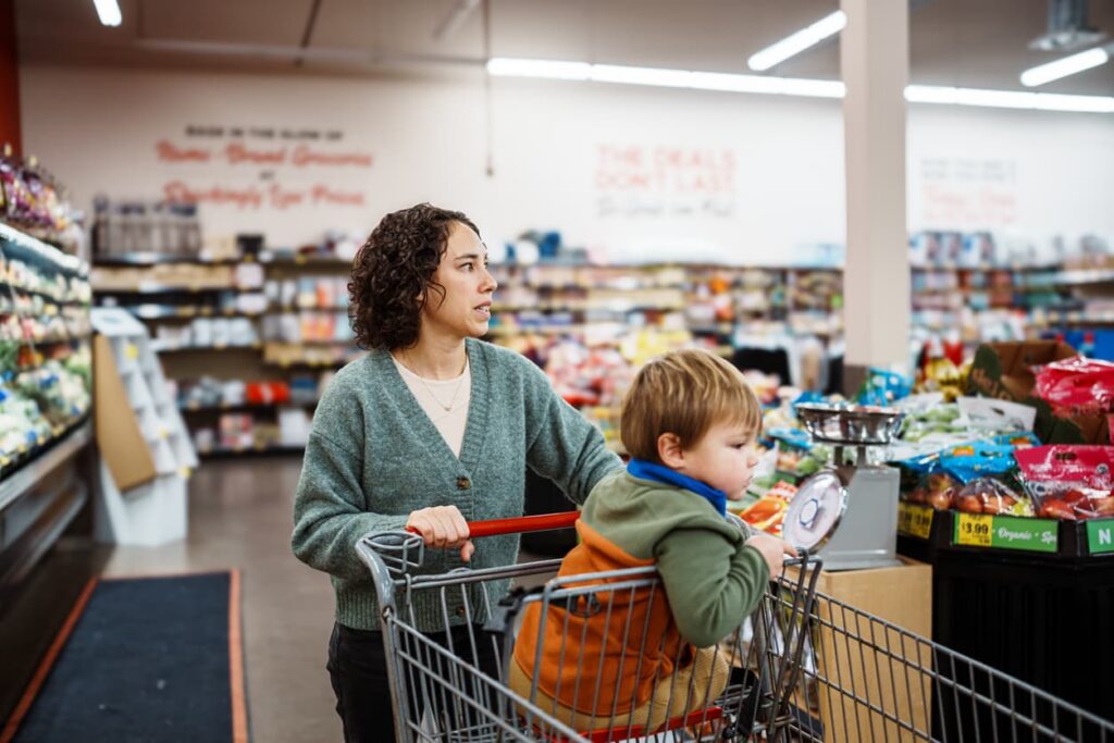 Mother and Child Shopping for Household Products at Grocery Store Mother shopping at grocery store with young child in cart, highlighting everyday consumer use of household products and product safety risks